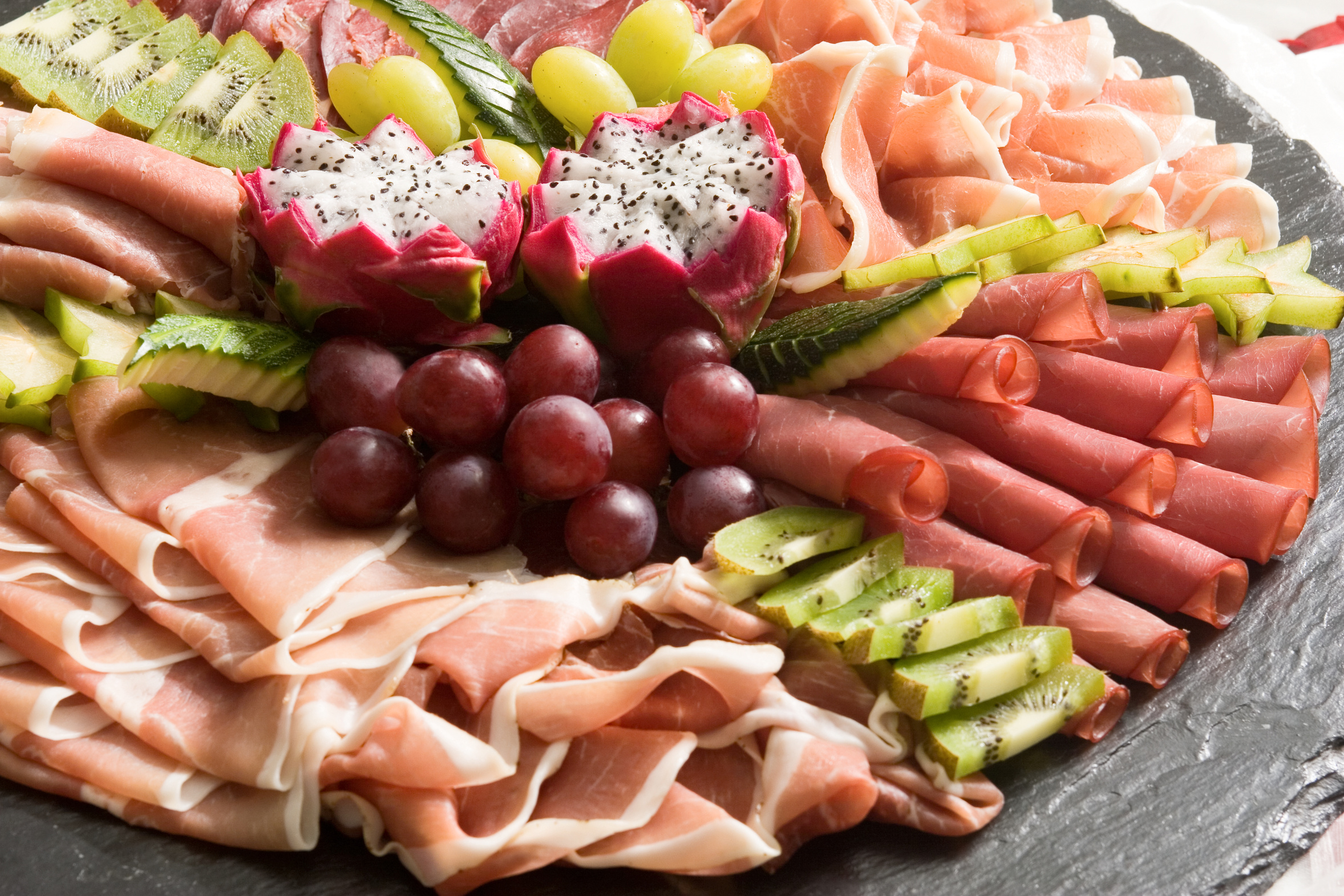 Frische gemischte Aufschnittplatte auf Schiefer mit Fruechten.